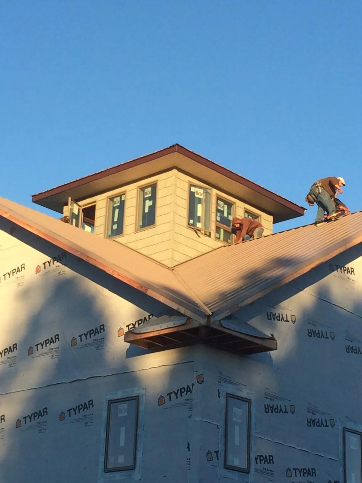 Roofers working around a rooftop cupola on a new metal roof at sunset — Roof Waterproofing in Hampton by Roofing Brothers
